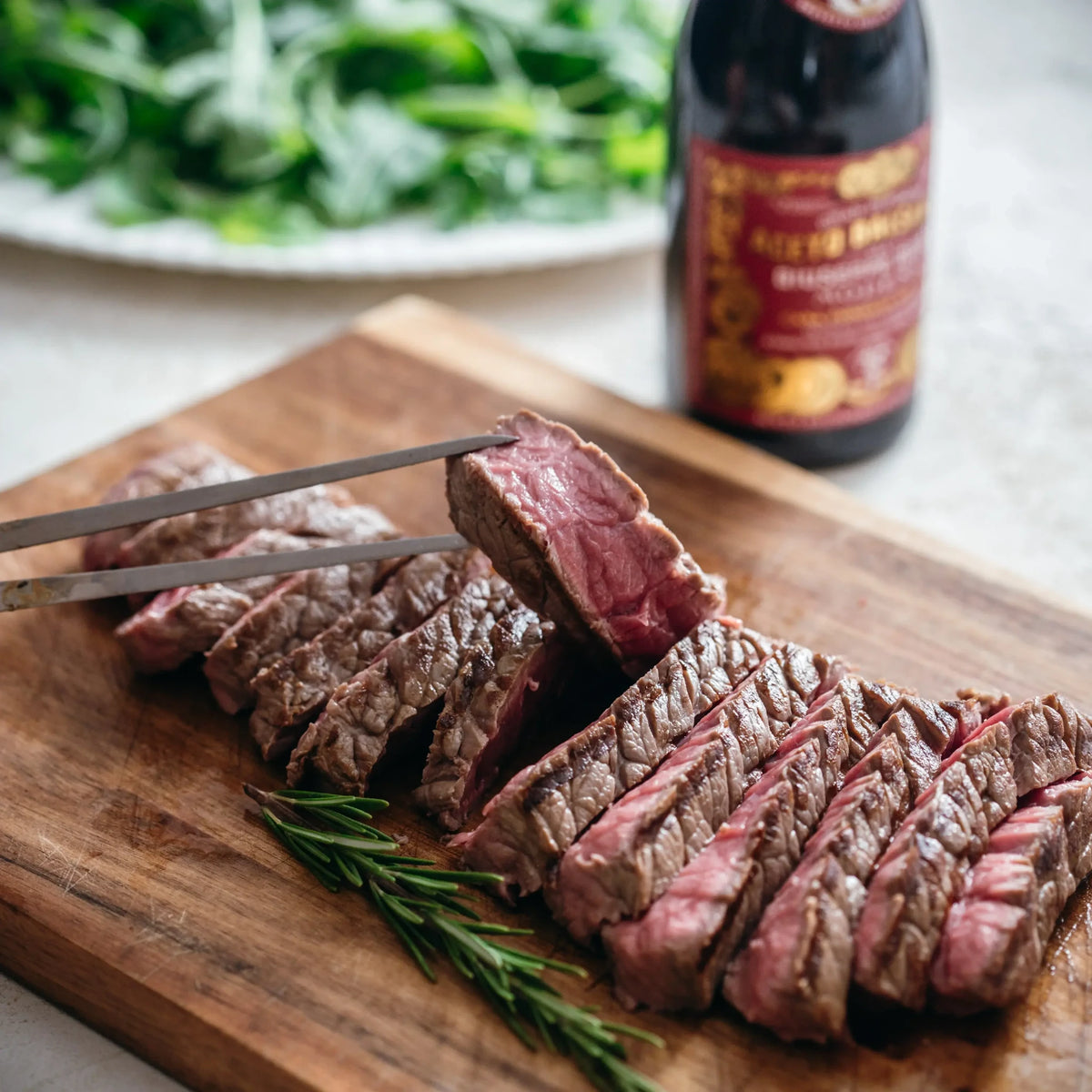 Sliced beef steak on a bed of arugula with Parmigiano shavings and balsamic glaze